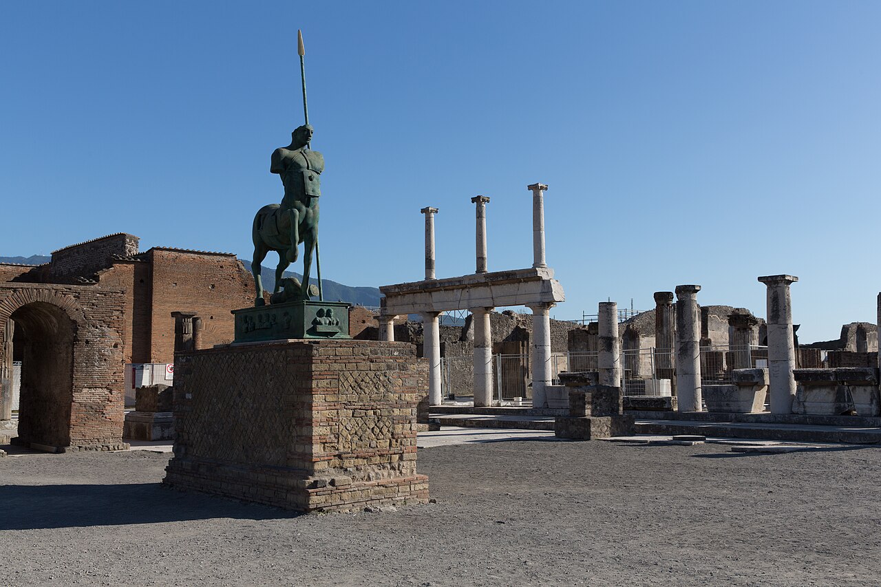 Stone columns of the Pompeii Forum in front of the Basilica ruins, with the Campanian landscape behind
